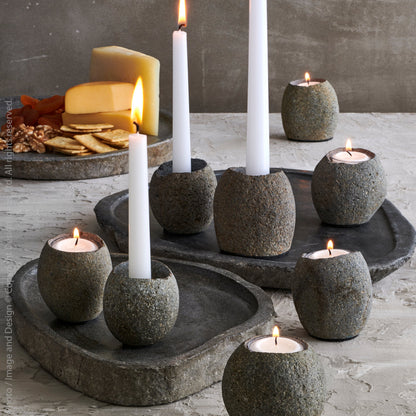 Lit tealight candles in stone candleholders on a dinner table